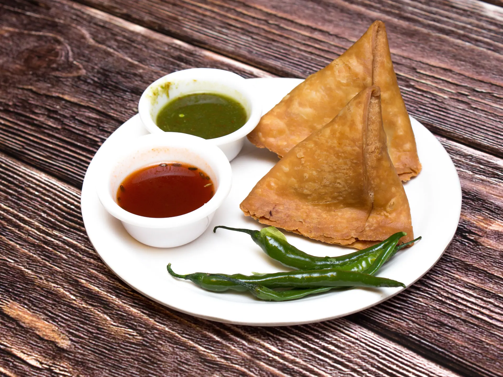 Crispy samosas with chutney and green chillies